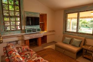 a living room with a couch and a tv at Fazenda do Rosa in Praia do Rosa