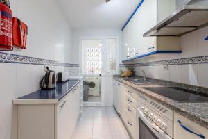 uma cozinha branca com um lavatório e uma máquina de lavar louça em marina duquesa 519 em Manilva