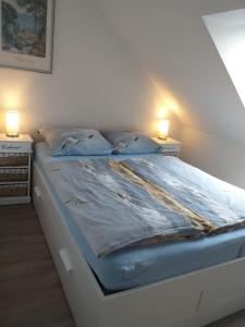Una cama blanca con dos lámparas encima. en Wohlfühlquartier Louisenlust, en Eutin