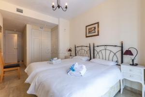 1 dormitorio con 2 camas con sábanas blancas y lámpara de araña en marina real 425, en Manilva
