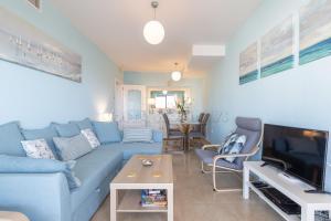 een woonkamer met een blauwe bank en een tv bij marina duquesa 256 in Manilva