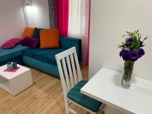 sala de estar con sofá y mesa con un jarrón de flores en La Apartamento Centroom en Jagodina