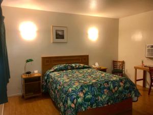 a bedroom with a bed with a floral bedspread at Sunrise Inn in Turlock