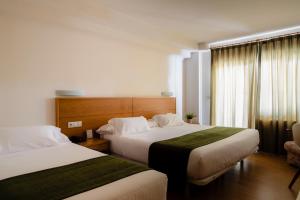 ein Hotelzimmer mit 2 Betten und einem Stuhl in der Unterkunft Hotel Crisol de las Rías in Miño