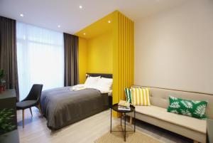 a bedroom with a bed and a couch and a chair at Banana Apartments in Batumi
