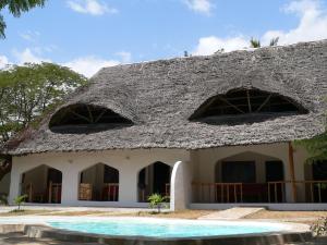 a house with a thatched roof and a swimming pool at Ocean Sports Resort in Watamu