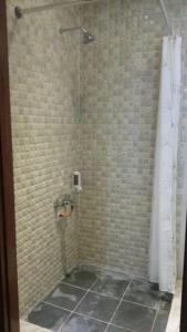 ein Bad mit einer Dusche und Fliesenboden in der Unterkunft Fam Sugiono Cottage - Studio House in Kemadang