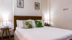 a bedroom with a bed with white sheets and green pillows at Talisay Boutique Hotel in El Nido