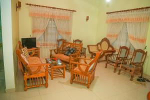 a living room filled with wooden chairs and a tv at Hasaranga Holiday House in Hikkaduwa