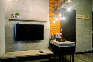 Zimmer mit einem Wand-TV und einem Tisch in der Unterkunft Homey 1BR at 15th Floor Apartment at Atlanta Residences By Travelio in Depok