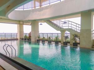 einen Pool mit einer Treppe in einem Gebäude in der Unterkunft Homey 1BR at 15th Floor Apartment at Atlanta Residences By Travelio in Depok