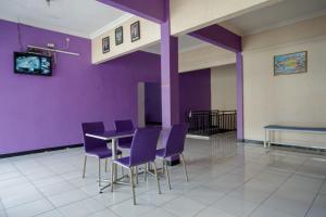 ein Esszimmer mit lila Wänden, einem Tisch und Stühlen in der Unterkunft RedDoorz near RSUD Kebumen in Kebumen