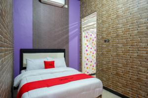 een slaapkamer met een bed en een bakstenen muur bij RedDoorz near Stasiun Kebumen in Kebumen