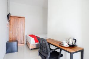 Habitación con escritorio, cama, mesa y silla. en RedDoorz Plus Syariah near Stasiun Tegal 2, en Tegal