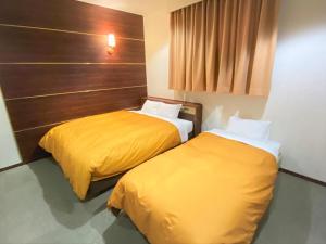 two beds in a hotel room with yellow sheets at Hotel 1-2-3 Kokura in Kitakyushu