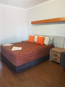 Ce lit se trouve dans un dortoir doté d'oreillers orange et blancs. dans l'établissement Safari Lodge Motel, à Tennant Creek