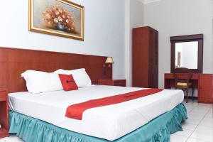 1 dormitorio con 1 cama grande con manta roja en RedDoorz near Kampung Warna Warni en Malang