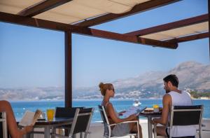 a group of people sitting at tables with a view of the ocean at Remisens Hotel EPIDAURUS in Cavtat