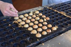 a person is cooking food on a grill at Hostel Takeyado in Osaka