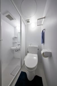 a white bathroom with a toilet and a sink at Hostel Takeyado in Osaka