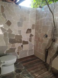 a bathroom with a toilet and a stone wall at Tevana House Reef in Bira