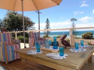 a wooden table with chairs and an umbrella at Baywater in Kingscote