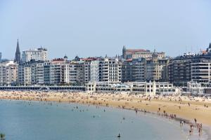 a group of people on a beach with buildings at Hotel Niza in Donostia-San Sebastián
