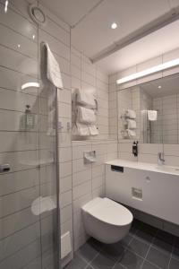 a bathroom with a toilet and a sink and a shower at Skara Konsthotell in Skara