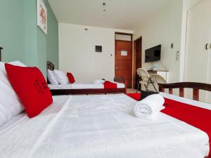 ダバオシティにあるRedDoorz Plus near Bangko Sentral Ng Pilipinas Davaoのベッドルーム1室(ベッド2台、赤と白の枕付)