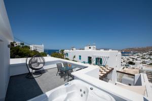 a balcony with a tub and a table and chairs at Zannis Hotel in Mikonos
