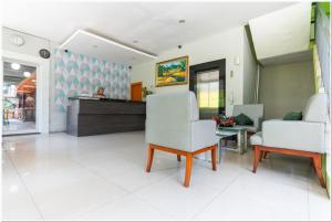 un vestíbulo con 2 sillas blancas y un mostrador en RedDoorz Plus @ Hertasning Area en Makassar
