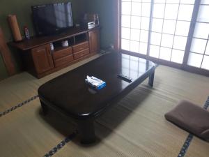 - Mesa de centro negra en la sala de estar con TV en Hostel Amaou, en Oki