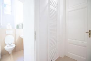 biała łazienka z toaletą i drzwiami w obiekcie HeyMi Apartments Stadtpark w Wiedniu