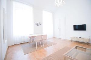 biały salon ze stołem i krzesłami w obiekcie HeyMi Apartments Stadtpark w Wiedniu