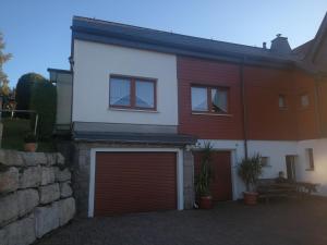 a white and red house with a garage at Ferienwohnung am Aschberg in Klingenthal