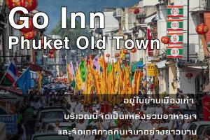 una multitud de personas caminando por una calle con banderas en Go Inn Phuket old Town en Phuket