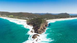 an aerial view of a beach with rocks in the ocean at Blue Vogue Apt at Blueys Beach in Blueys Beach