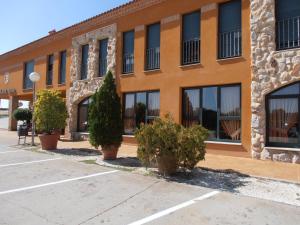 un bâtiment oranger avec des arbres devant lui dans l'établissement Hotel Cañada Real, à Villalpando