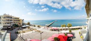 Blick auf einen Strand mit rosa Sonnenschirmen und das Meer in der Unterkunft Luxury Plateia Rooms in Peraia