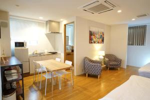 a kitchen and a living room with a table and chairs at Santiago Guesthouse Hiroshima in Hiroshima