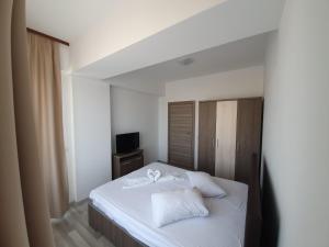 a bedroom with a white bed and a television at Niko Apartment in Mamaia
