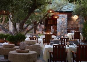 a restaurant with tables and chairs with wine glasses at Elounda Peninsula All Suite Hotel, Six Senses Spa in Elounda