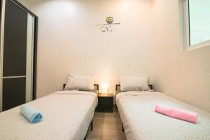 two beds sitting next to each other in a room at Landed Cozy House Near SPICE, Airport in Kampong Manggis