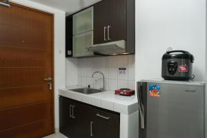 a small kitchen with a sink and a refrigerator at Elegant Studio Apartment at Margonda Residence 2 By Travelio in Depok