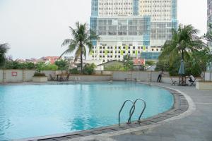 a large swimming pool in a city with tall buildings at Elegant Studio Apartment at Margonda Residence 2 By Travelio in Depok