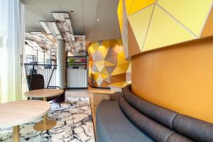 un hall avec une table et un mur jaune dans l'établissement B&B HOTEL Paris Porte des Lilas, à Paris