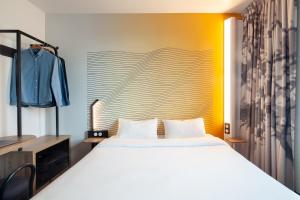 巴黎B&B HOTEL Paris Porte des Lilas的卧室配有一张白色大床和一堵墙