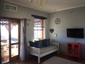 Una sala de estar con un sofá y un televisor de pantalla plana. en Sea View Charming Stone House, en Mossel Bay