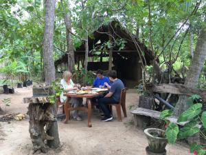 eine Gruppe von Menschen, die an einem Tisch mit Essen sitzen in der Unterkunft Yapahuwa Relax Stay in Yapahuwa