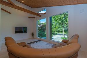 - un salon avec un canapé et une grande fenêtre dans l'établissement Villa Wellstone O'sam, à Hakuba